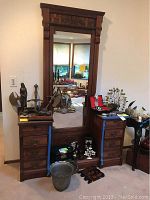 Full view of the vintage wooden dresser with carved details, mirror, and various items on top and inside the drawers opened for display.