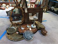 Full lot overview showing gold mirrors, wooden tray, brass trays, glass candlestick and decorative box.