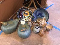 Collection of pottery ducks, bowls, cups and other pottery decor items grouped on floor showing colors, shapes, and textures.