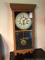 Full view of the Sessions Regulator clock showing front wooden case, glass panel and clock face with calendar numbers.
