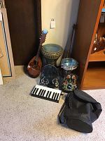 Overview of lot showing mandolin at left, two goblet-style drums, snare drum, folded music stand, melodica and gig bag on floor