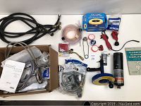 Full overview of the assorted plumbing tools and Kohler kitchen faucet with packaged items and accessories on a white surface.