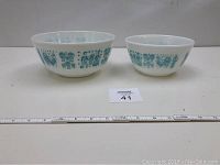 Two Pyrex Butterprint pattern bowls placed side by side showing size difference and full pattern
