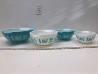 Four Pyrex Cinderella nesting bowls arranged in size order from smallest to largest with ruler for scale.