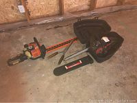 Stihl hedge trimmer and Troy-Bilt chainsaw positioned side by side on garage floor
