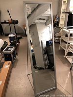 Tall rectangular EQ3 standing mirror with gray frame shown from front in basement room with equipment