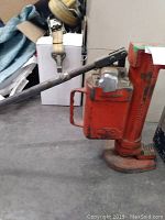 Front left angle view of hydraulic toe jack showing pump handle, base and toe plate.