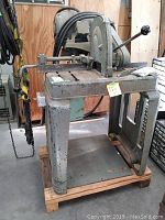 Full view of cast iron industrial metal cutting saw mounted on wood pallet base