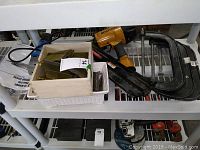 Overall lot showing Bostitch nail gun, two bins of nails and three C-clamps on shelf