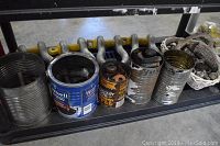 Shelving with collection of empty and filled cans containing assorted bolts, nuts, washers, and small hardware. Yellow hitch bar behind cans.