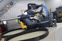 Side view of saw on metal cabinet with replacement belt coiled in front