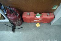 Milwaukee brand Sawzall in red carrying case next to Chapin tri-poxy lined steel tank sprayer