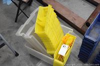Top view of a large translucent plastic bin containing stacks of yellow plastic storage caddies with compartments and dividers.
