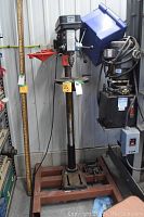 Full view of the Power Fist pillar drill press standing on steel base with associated wiring and nearby equipment.
