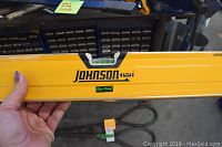 Close-up photo showing the yellow Johnson aluminum alloy level with 'Glo-View' branding and bubble vial.