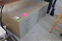 Full view of grey metal flat file cabinet on floor