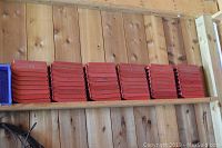 Shelf with multiple stacks of red plastic storage bins