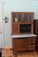 Full front view of oak Hoosier cabinet against wall