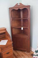 Full view of the solid wood corner cupboard showing its height, shelves, and lower door.