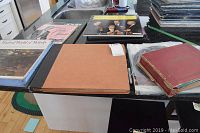 Overview of multiple vintage LP and 45 record albums on kitchen counter, includes various album covers and binders.