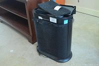 Black Honeywell air cleaner with foam pre-filters on top, showing some dust and lint.