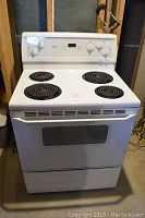 Full frontal image of the white electric range showing cooktop with four coil burners and oven door with large window.