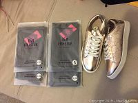 Four pairs of Empetua shape wear in original packaging and one pair of rose gold sneakers shown together.
