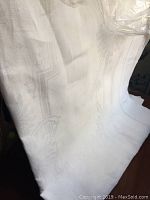 Close-up photo showing texture and subtle woven pattern of an antique white linen tablecloth with some folds and creases.