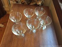 Top view of six clear glass custard dishes arranged on wooden table.