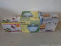 Photo shows three boxed items side by side: Starfrit Apple Peeler, Rice Cooker, and Thermal Gravy & Sauce Server.