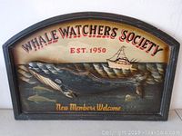 Front view of Whale Watchers Society sign showing painted whale, boat, and lettering