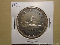 Reverse side of 1951 Canadian silver one dollar coin depicting canoe with two paddlers and date 1951 with inscriptions 'CANADA DOLLAR'.