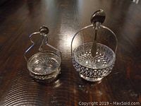 Two silver plated condiment trays with clear glass bowls on a dark wooden surface