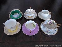 Top view of six assorted teacups and matching saucers in various designs and colors.