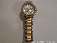 Full front view of DKNY watch showing two tone metal bracelet and circular face with crystals on bezel
