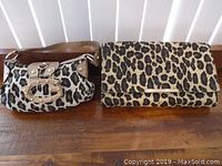 Photo of two small women's handbags on a wooden surface, one clutch style and one shoulder handbag, both with leopard print patterns.