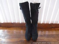 Front view of the pair of black leather women's boots showing pointed toes and mid-calf height