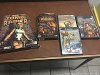 Photo showing all five PC video games from the lot, laid on a table.