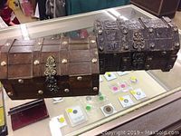 Two vintage wooden treasure chest style boxes with metal accents on display