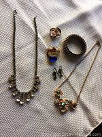 Overview photo showing entire jewelry lot including necklaces, rings, earrings, and bracelet on fabric background