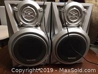 Front view of the two Venture branded speakers showing their design, grills, and wire connections.