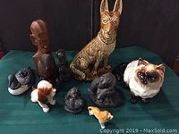 Lot of 10 assorted collectible figurines featuring animals and abstract sculptures seen from front angle on green cloth surface