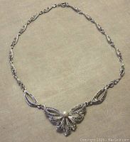 Full view of the silver-tone marcasite and faux pearl necklace laid flat showing the entire length and design with centerpiece