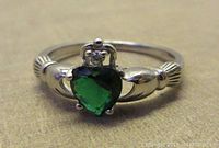 Close-up view of the front of the sterling silver Claddagh ring showing green heart-shaped stone and crown detail.