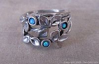 Front view showing leafy silver design and three small blue-green opal cabochons in the ring.