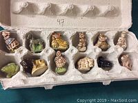 Overhead view of a total of 12 tea figurines placed individually in an egg carton style holder.