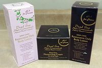 Set of three boxes of Dead Sea skincare products: two 250 ml body lotions (pink and dark brown boxes) and one 100 ml moisturizing cream (dark brown box) placed on a surface.