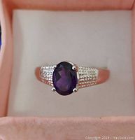 Front view of .925 sterling silver ring with oval purple amethyst stone set in prongs, displaying detailed textured band.