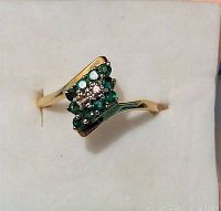 Top view of 14K yellow gold ring showing emerald and diamond cluster in presentation box