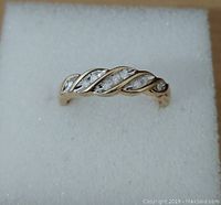 Top view of ring on white foam showing two-tone twisted design and nine diamonds